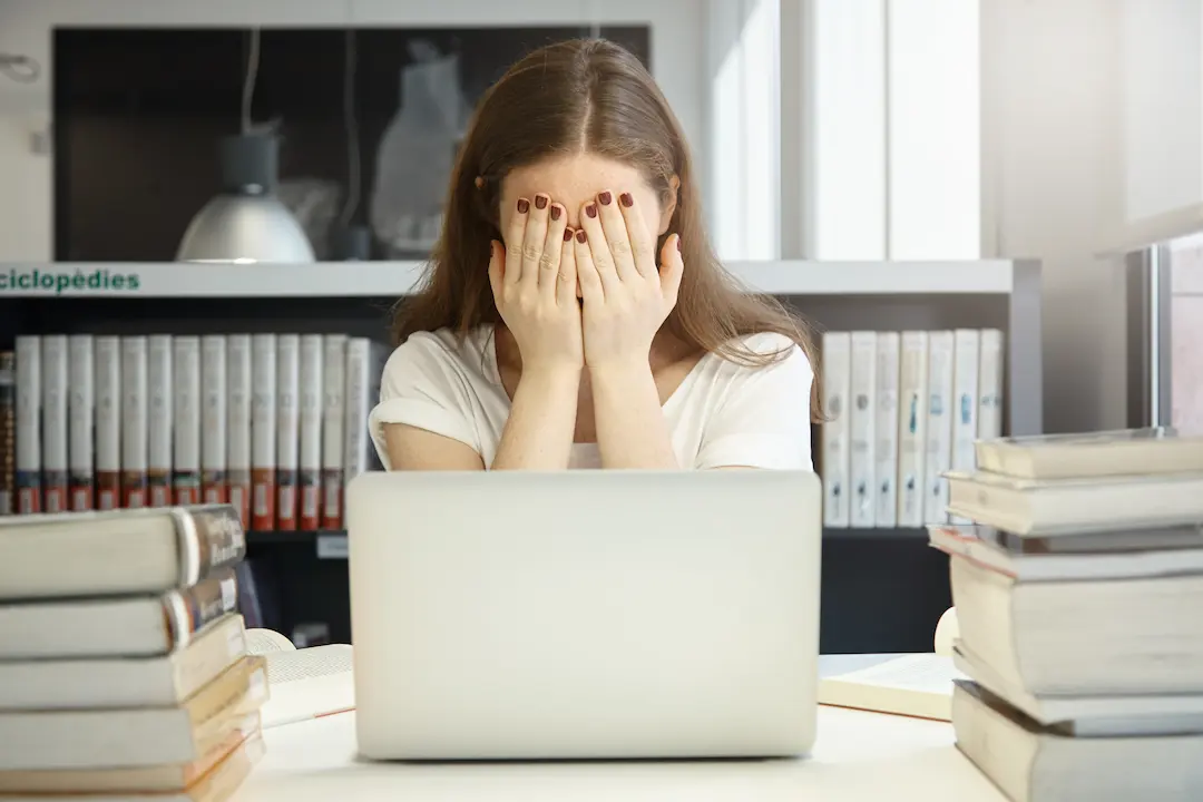 Joven con las manos en el rostro mostrando estrés postvacacional